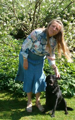 Foto - Rita Skov i haven sammen med førerhunden - foran et blomstende æbletræ